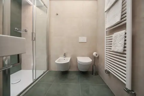 Baño con ducha de cristal y suelo verde