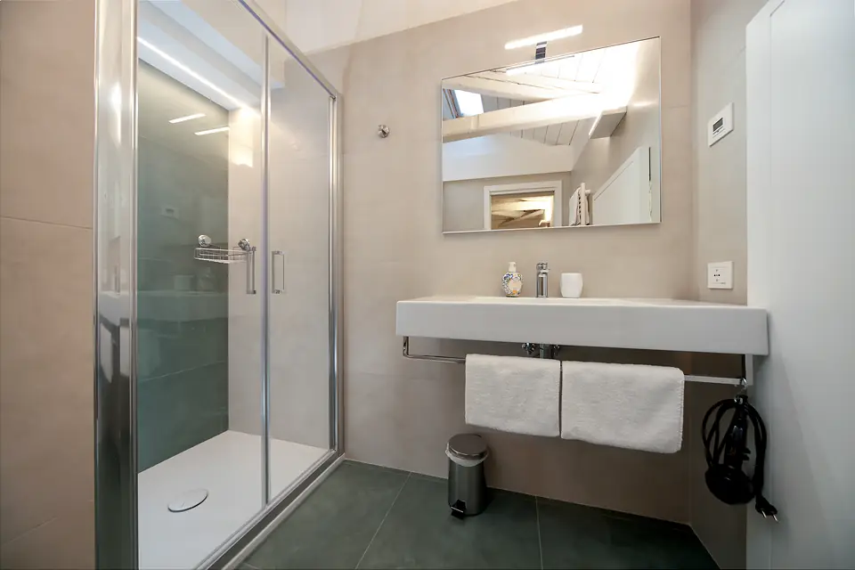 Ducha de cristal y lavabo con espejo iluminado