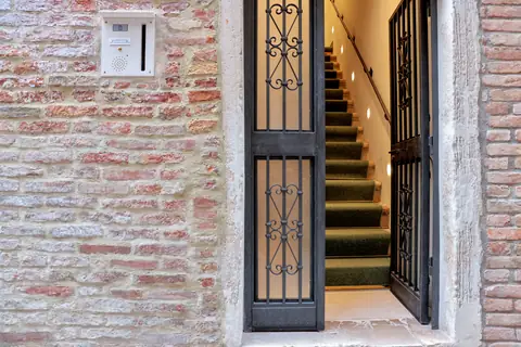 El portal de hierro abierto a la escalera verde