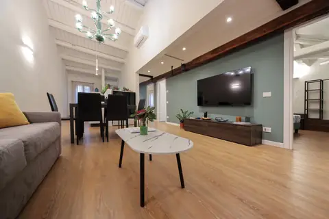 Sofá cama con cojines amarillos frente a la pared verde salvia