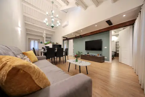 Salón con sofá, mesa de comedor y vigas blancas