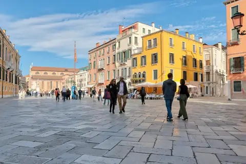 Una plaza veneciana con casas amarillas y paseantes